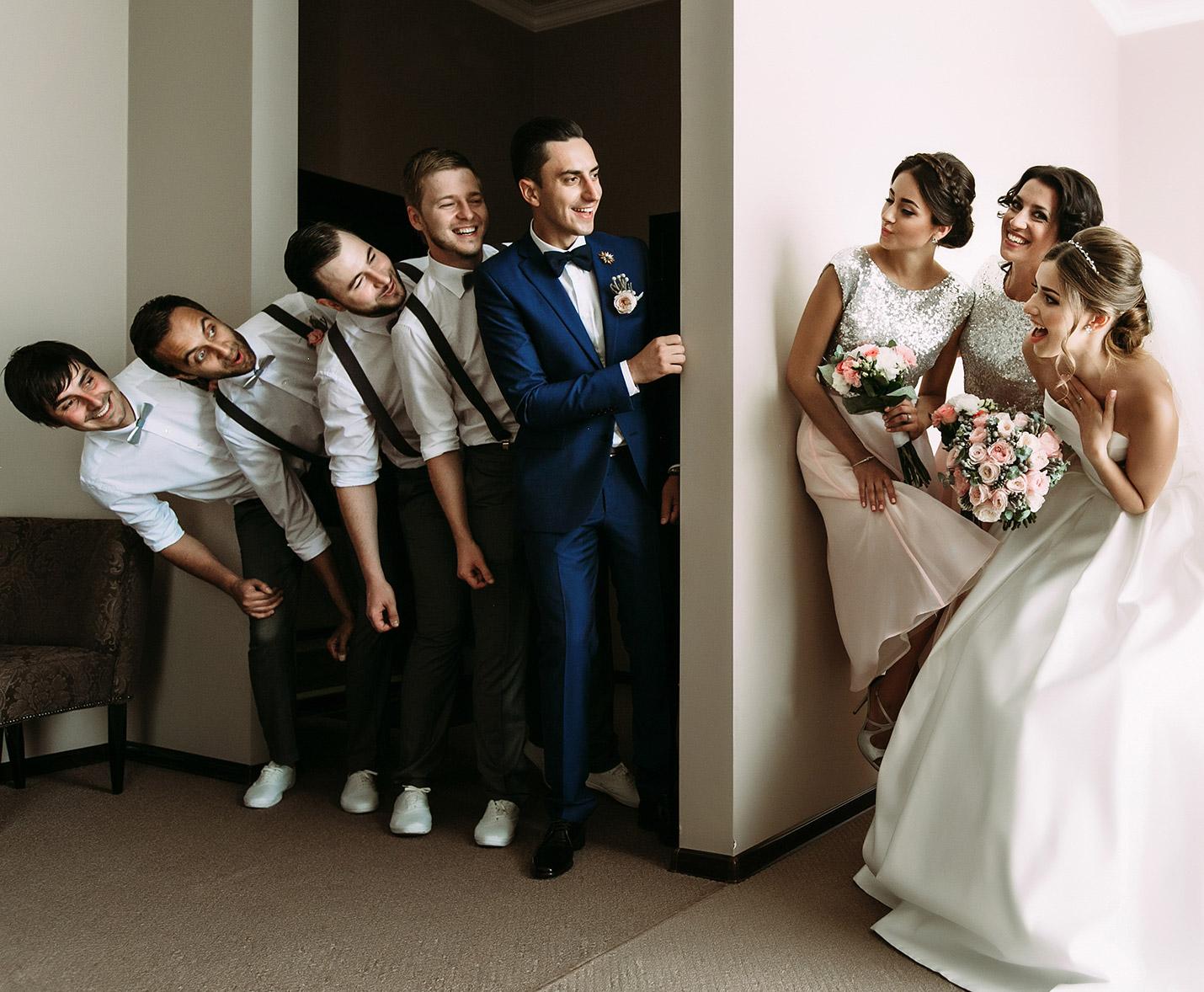 Groom and bridal party leaning past a wall